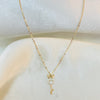 Gold key-shaped necklace with a small pendant on a white surface