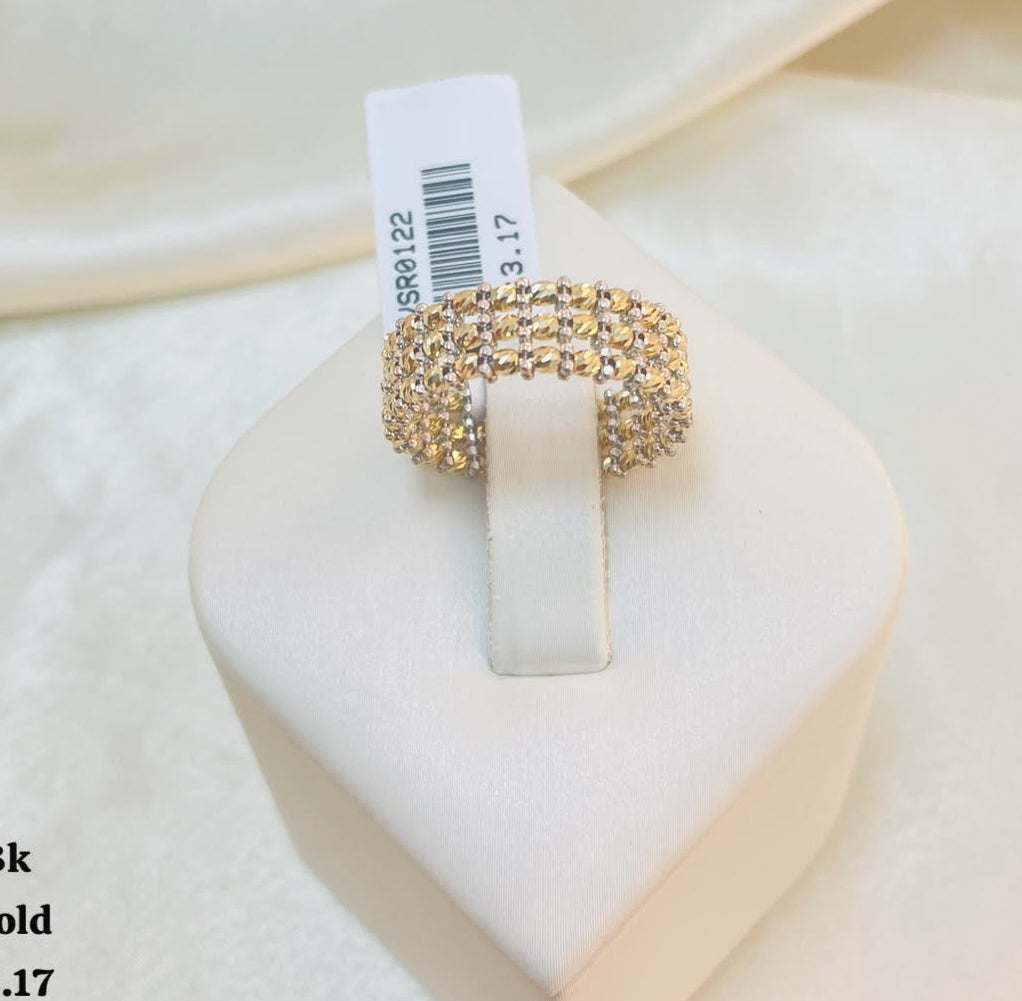 A yellowgold ring with a triple-row pave setting of clear stones, displayed on a white heart-shaped jewelry stand. The background is a soft beige satin fabric.