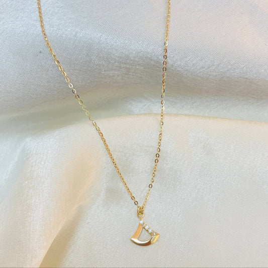 Gold necklace with a unique pendant on a white fabric background