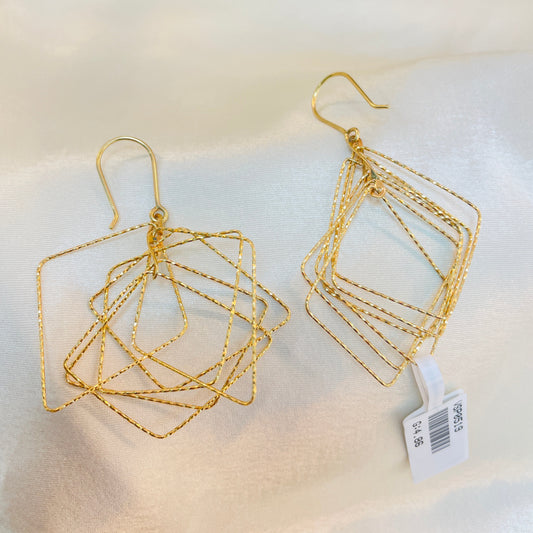 Gold geometric earrings on a mannequin with a visible tag.
