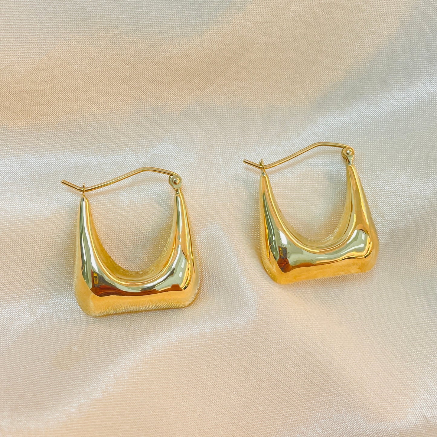 Gold hoop earrings on a light fabric background