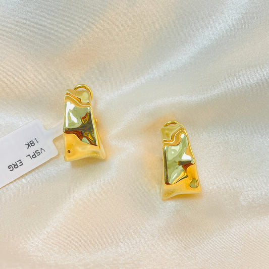 Gold earrings with green gemstones on a white satin background