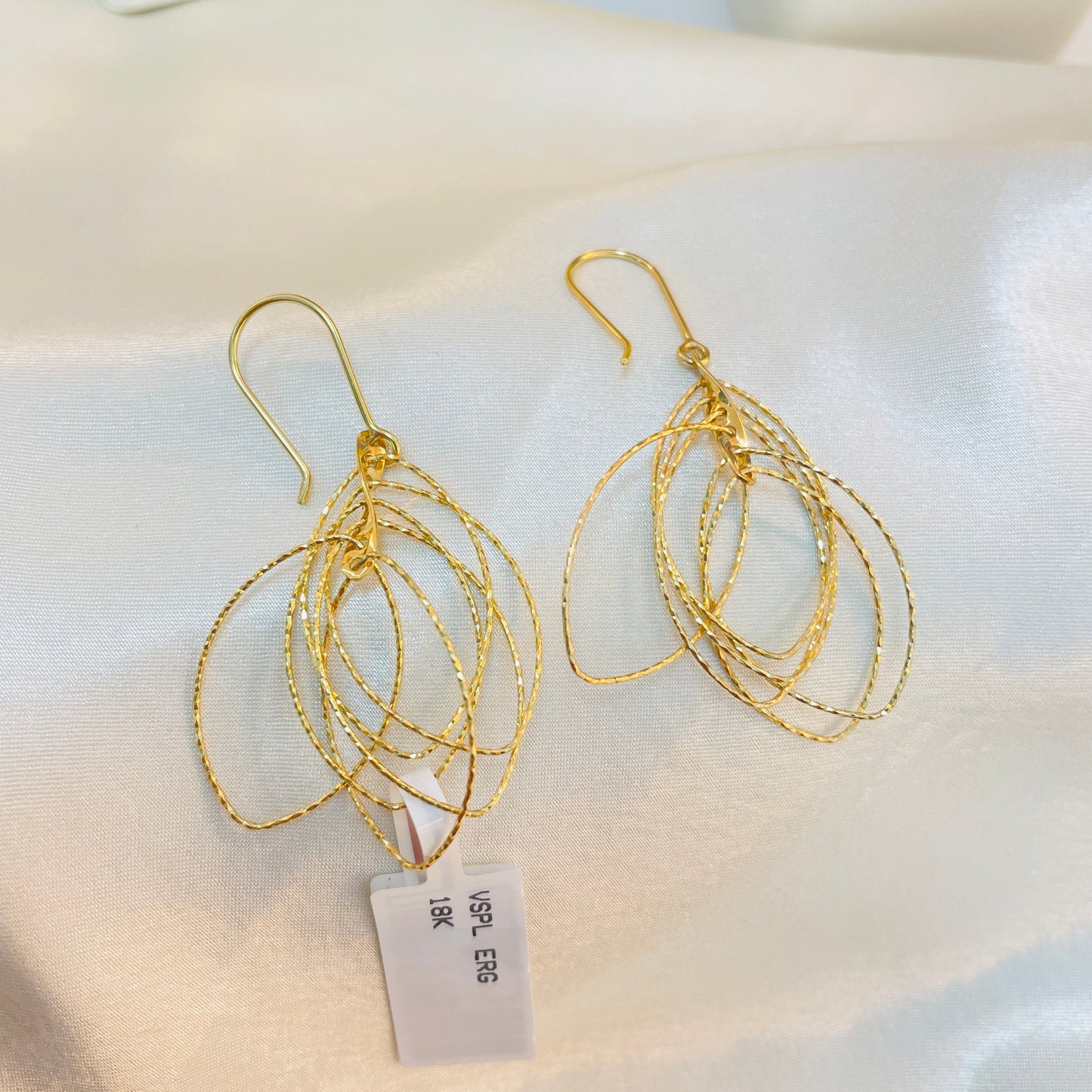 Gold earrings with a price tag on a white surface