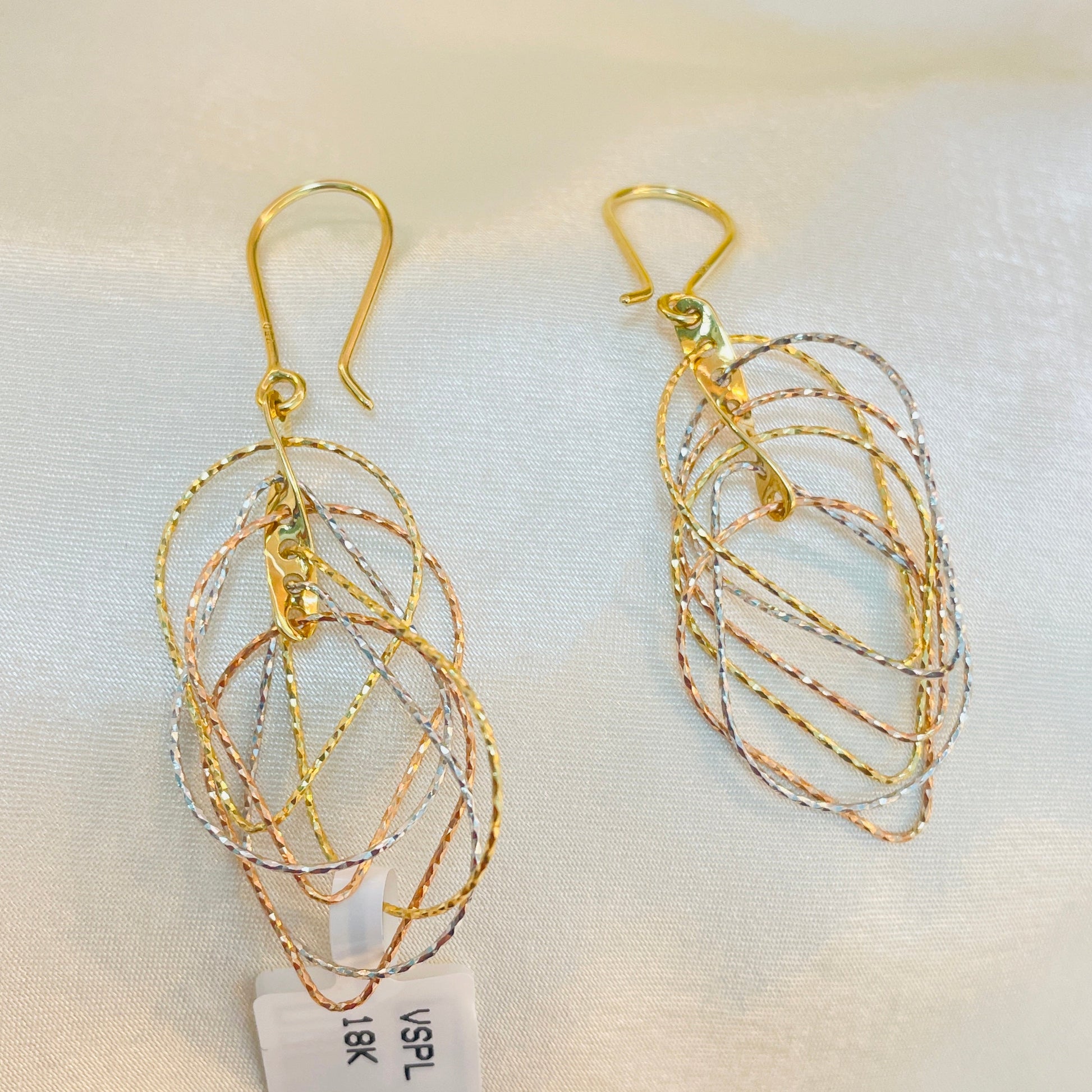 Gold and silver layered earrings on a white background with a tag.