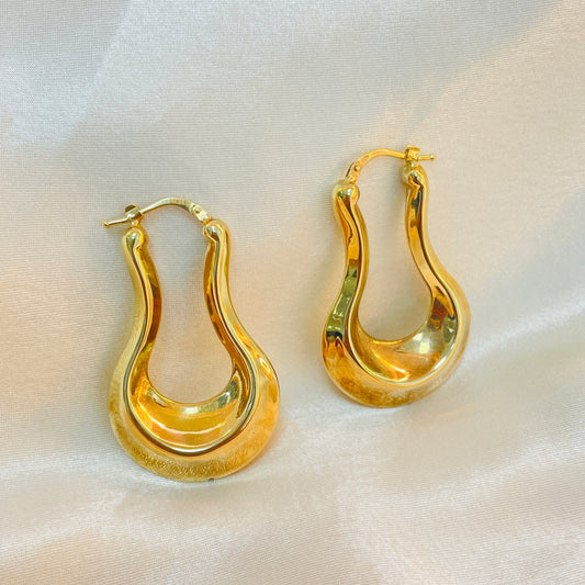 Pair of gold hoop earrings on a white fabric background