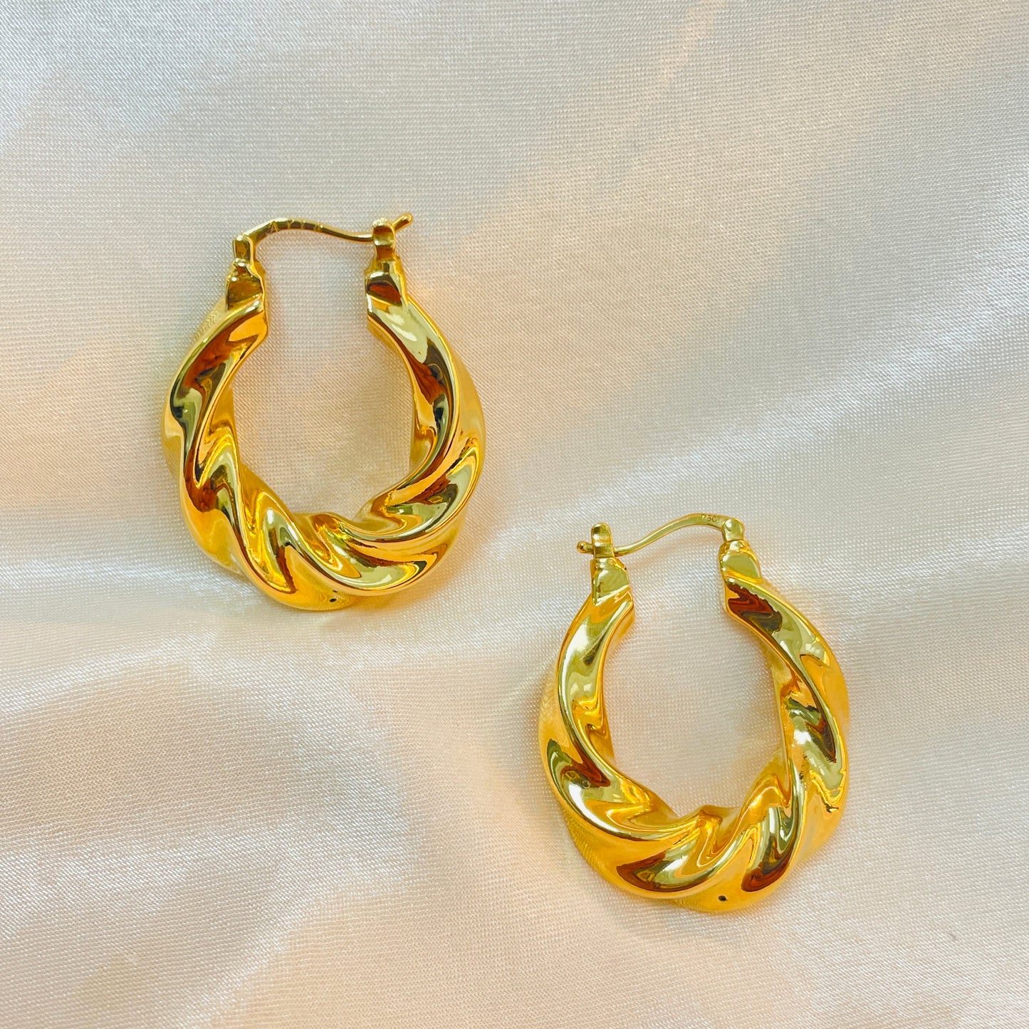 Pair of gold hoop earrings on a light fabric background
