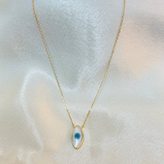 Gold necklace with a blue eye-shaped pendant on a light fabric background