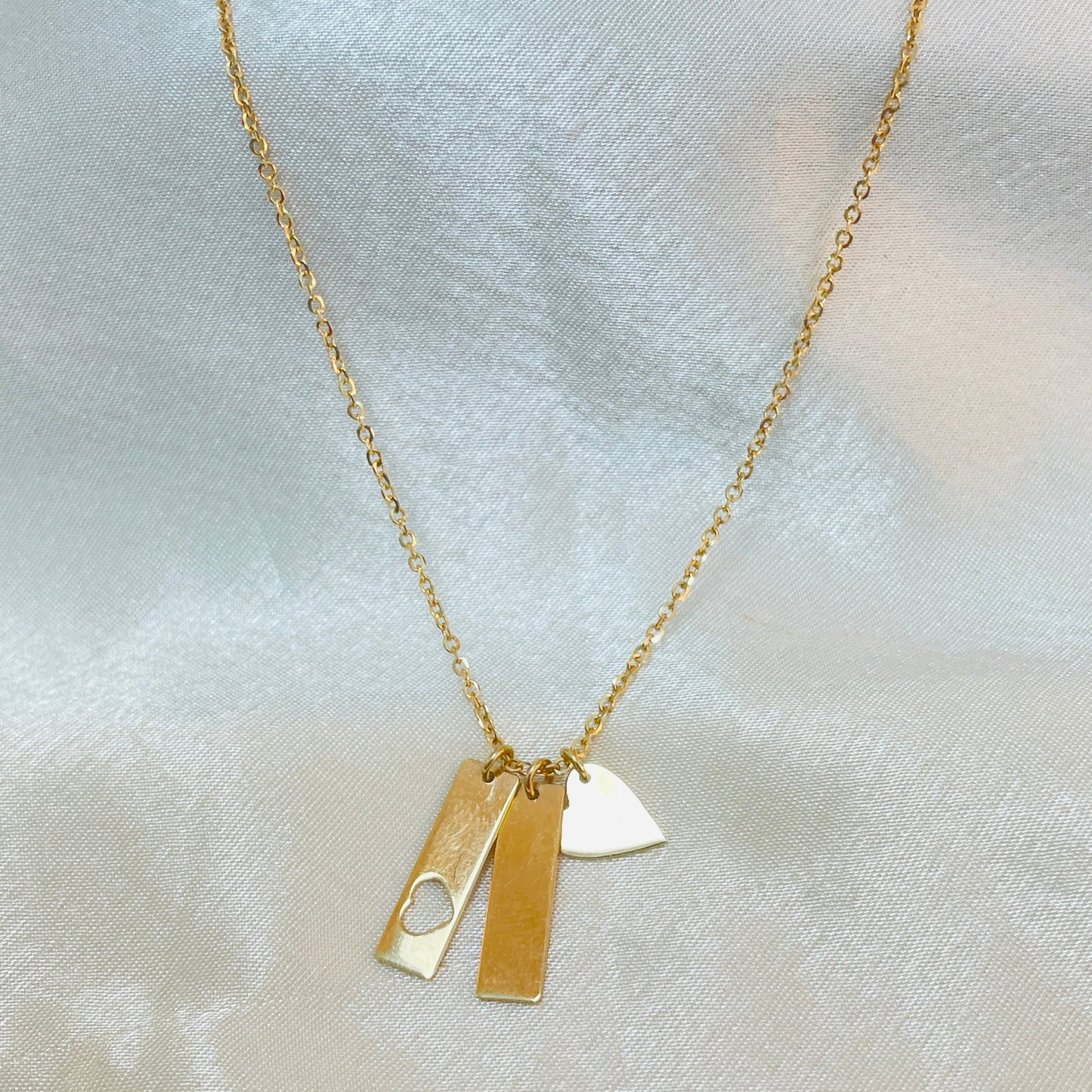 Gold necklace with two pendants on a light fabric background
