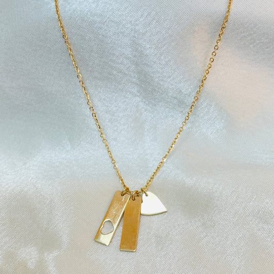 Gold necklace with two pendants on a light fabric background