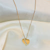 Gold heart-shaped necklace with a pendant on a white fabric background