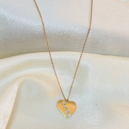 Gold heart-shaped necklace with a pendant on a white fabric background