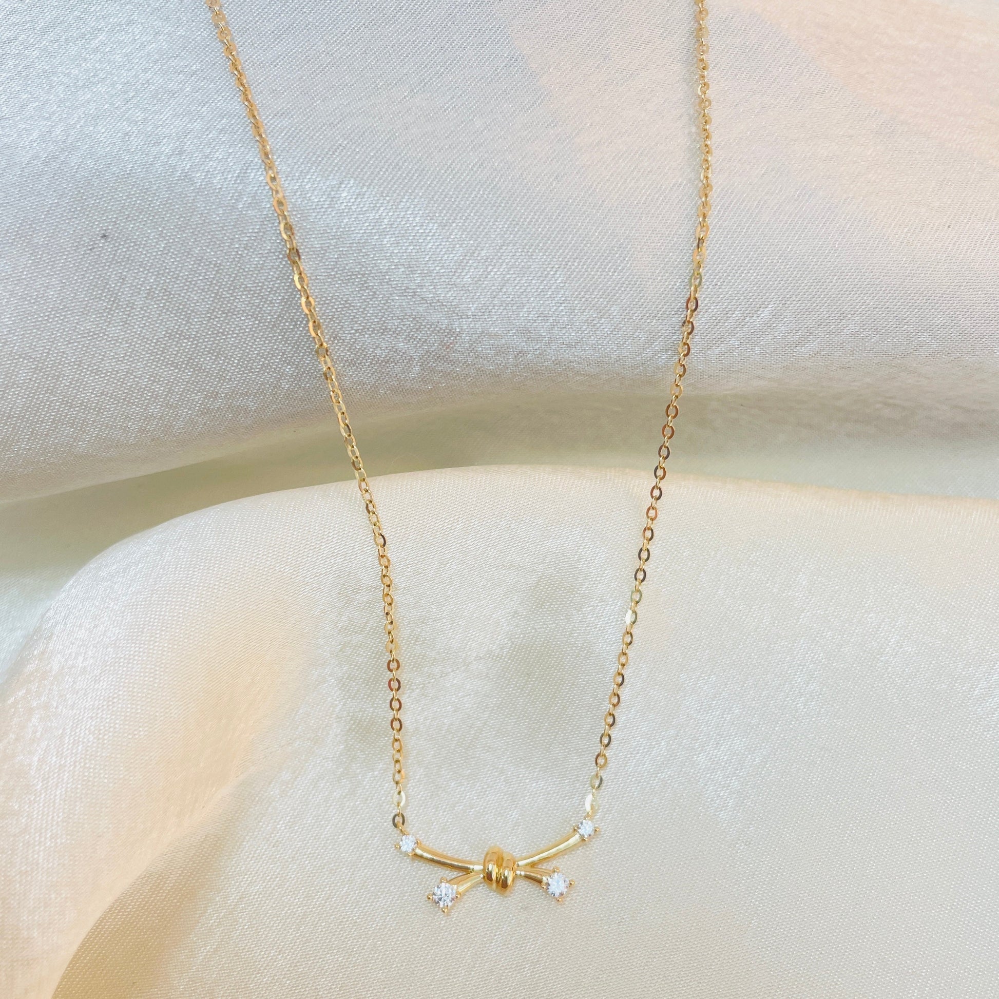 Gold necklace with a delicate pendant on a white fabric background