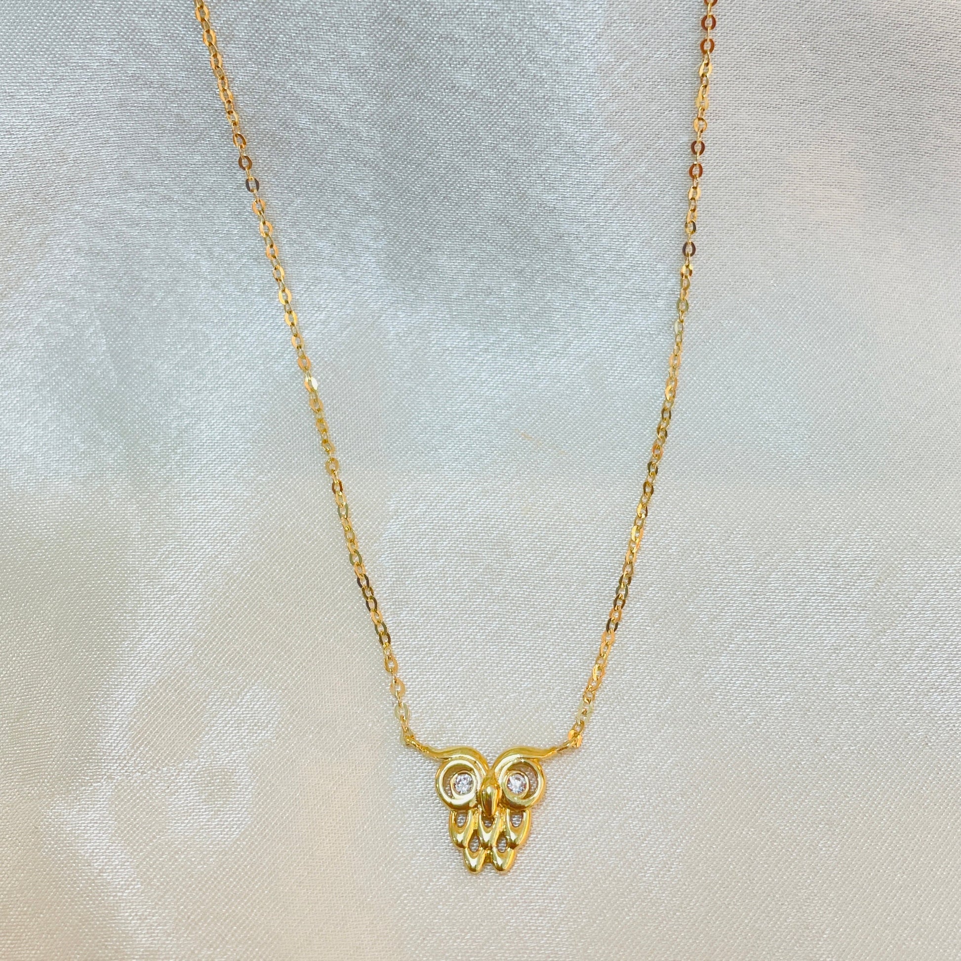 Gold necklace with a small pendant on a light gray background