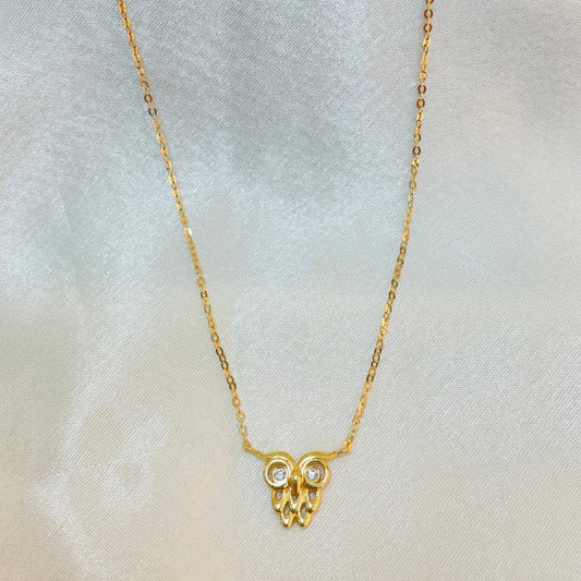 Gold necklace with a small pendant on a light gray background