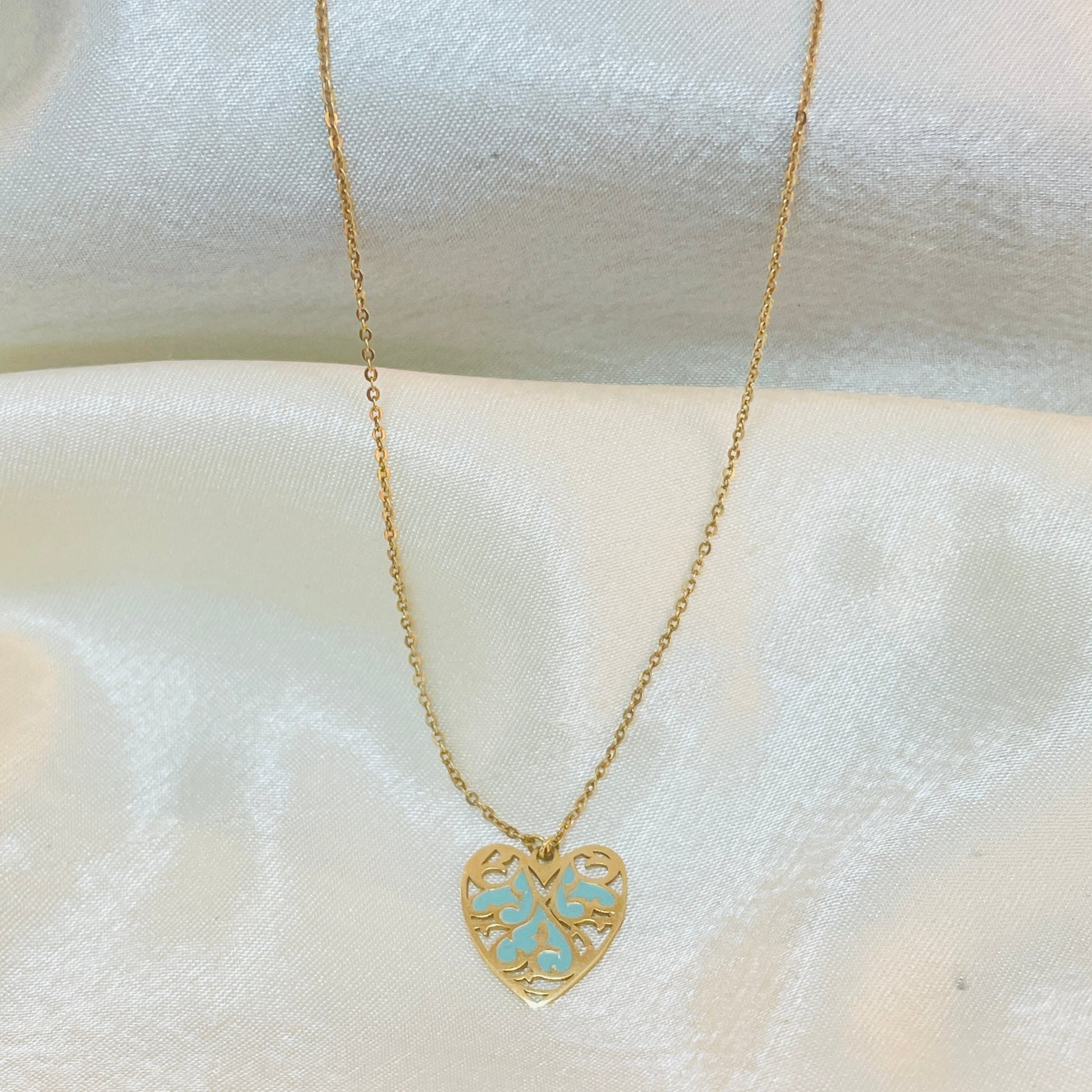 Gold necklace with a heart-shaped pendant on a white fabric background